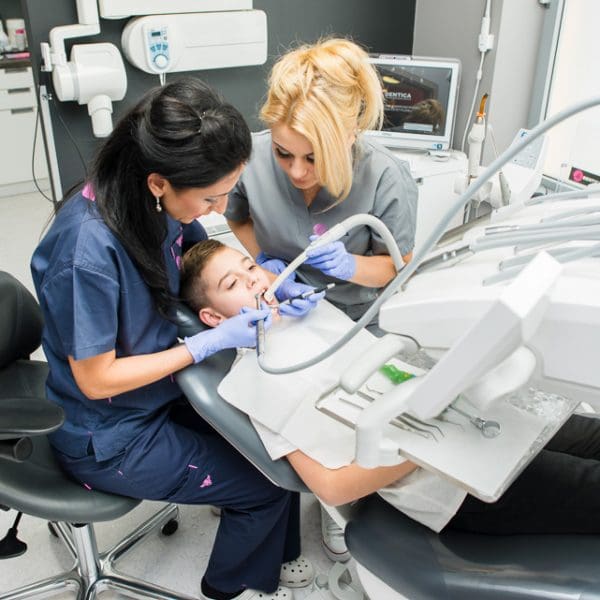 Zabieg dentystyczny przeprowadzany u małego chłopca z pomocą